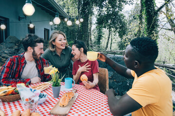 laughing friends having breakfast outdoor in holiday home