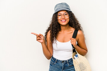 Young hispanic woman wearing a beach bag isolated on white background smiling and pointing aside, showing something at blank space. - Powered by Adobe