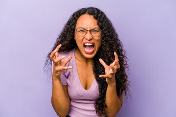 Young hispanic woman isolated on purple background upset screaming with tense hands.