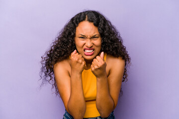 Young hispanic woman isolated on purple background upset screaming with tense hands.