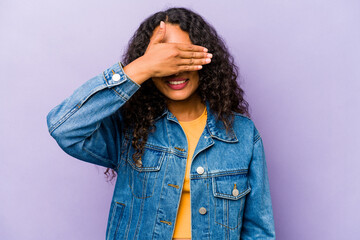 Young hispanic woman isolated on purple background covers eyes with hands, smiles broadly waiting for a surprise.