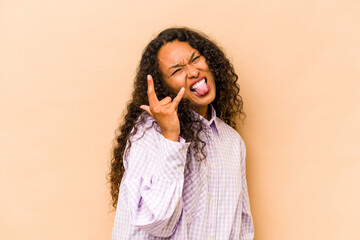 Young hispanic woman isolated on beige background showing rock gesture with fingers