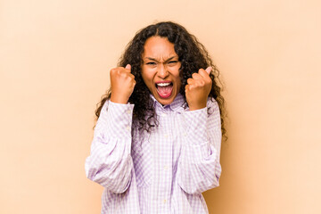Young hispanic woman isolated on beige background cheering carefree and excited. Victory concept.