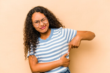 Young hispanic woman isolated on beige background having a liver pain, stomach ache.