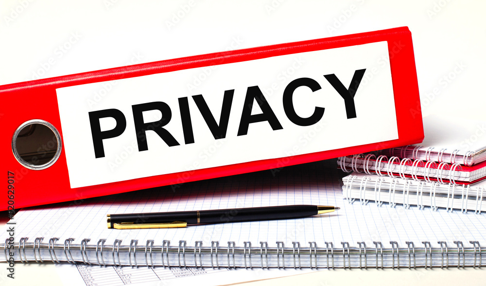 Poster on the desktop are notebooks, a pen and a red folder for papers with the text privacy. business conc