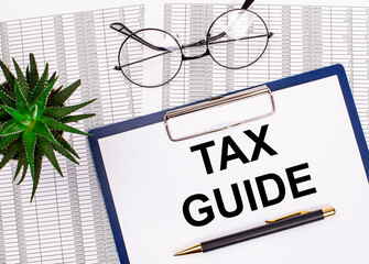 Folded business papers, pen, glasses, a flower in a pot and a tablet with a sheet of paper with the...