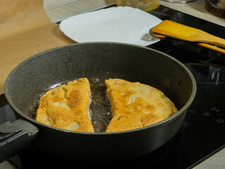 cooking chebureks laid out in a frying pan close-up