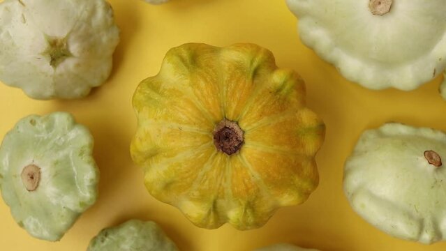 Pattypan squashes on a yellow background. Top view. Rotate 360 degrees.