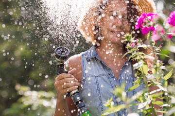 A girl with a watering hose in close-up. The farmer's wife is watering the flowers. The concept of...