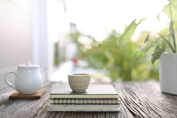 White tea cup and vintage tea pot and small plants on wooden table