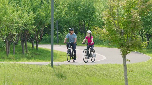 Happy mature couple riding bikes in park,4K