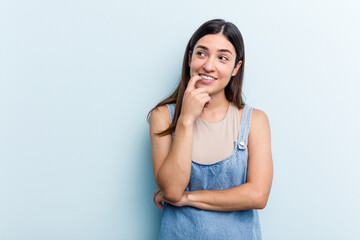 Young caucasian woman isolated on blue background relaxed thinking about something looking at a copy space.