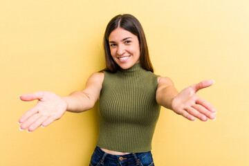 Young caucasian woman isolated on yellow background showing a welcome expression.