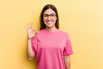 Young caucasian woman isolated on yellow background cheerful and confident showing ok gesture.