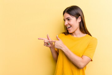 Young caucasian woman isolated on yellow background points with thumb finger away, laughing and carefree.