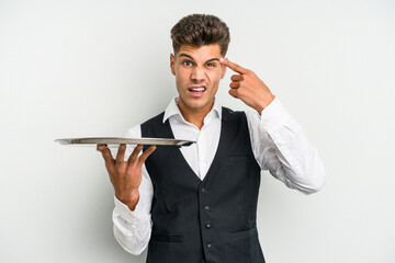 Young caucasian waitress man holding a tray isolated on white background showing a disappointment...