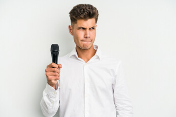 Naklejka premium Young singer caucasian man isolated on white background confused, feels doubtful and unsure.