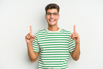 Young caucasian man isolated on white background indicates with both fore fingers up showing a...