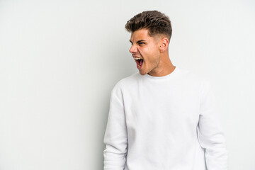 Young caucasian man isolated on white background shouting very angry, rage concept, frustrated.