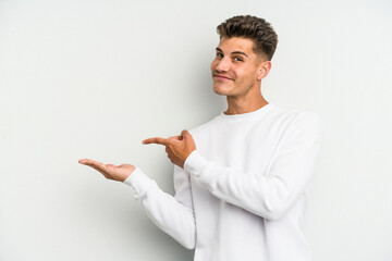 Young caucasian man isolated on white background excited holding a copy space on palm.