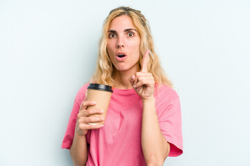 Young caucasian woman holding a take away coffee isolated on blue background having some great idea, concept of creativity.