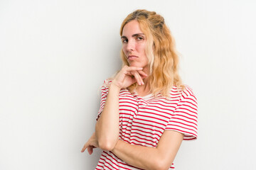 Young caucasian woman isolated on white background suspicious, uncertain, examining you.