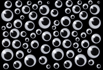 Googly eyes are small plastic craft supplies used to imitate eyeballs isolated on black background. - 520637208