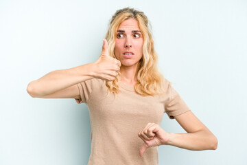 Young caucasian woman isolated on blue background showing thumbs up and thumbs down, difficult...
