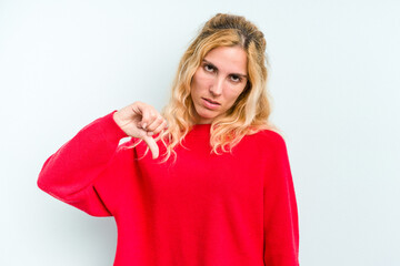 Young caucasian woman isolated on blue background showing a dislike gesture, thumbs down....