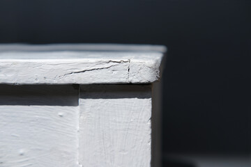 corner of a white painted aged table in profile outline in the shadows close-up, rustic vintage stool chair