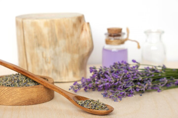 Dry lavender flowers in wooden bowl and bottle of essential lavender oil or infused water on white background. Natural organic ingredients for herbal cosmetics. Spa massage set, lavender product