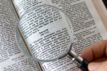 Scripture verses for faithful Christian rewards in an open Holy Bible Book and a magnifying glass....