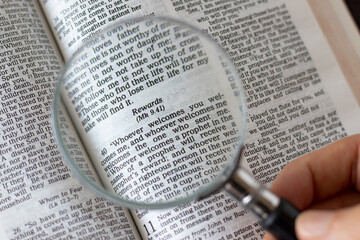 Obraz premium Scripture verses for faithful Christian rewards in an open Holy Bible Book and a magnifying glass. A close-up. The biblical concept of blessings from God Jesus Christ.