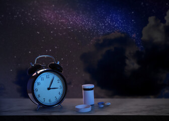Alarm clock and soporific pills on grey table against night sky with stars. Insomnia