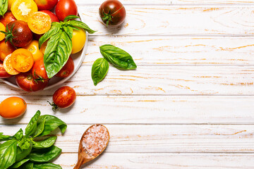 Fresh juicy tomatoes, basil leaves and Himalaya salt on white wooden background top view, copy...