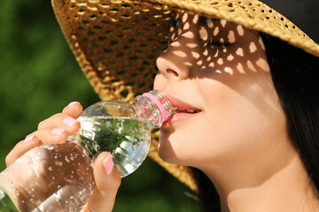 Beautiful young woman drinking water outdoors, closeup. Refreshing drink