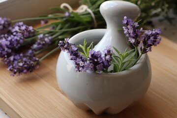 Obraz na płótnie Canvas Mortar with fresh lavender flowers, rosemary and pestle on wooden table
