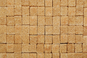 Brown sugar cubes as background, top view
