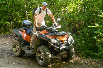 Fototapeta na wymiar Young man driving off road adventure with happy and smiling. Man riding on ATV bike or quad bike on road along forest trail on mountain. Camping, jungle adventure concept.