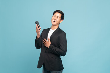 Young asian man in suit and jeans for smart casual business concept using smart phone isolated on blue background