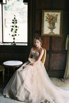 Bride sits on a chair at a table near the window of an old villa. Como, Italy