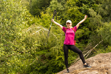 Fototapeta na wymiar Woman hiking in the mountains. Hiking with a backpack and sticks.