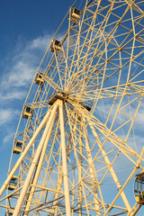 Entertainment attraction. Ferris wheel on a blue sky background.