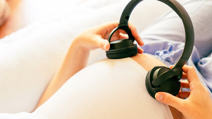 Baby music pregnancy woman. Cheerful pregnant girl relaxing listening music in headphones. Mother belly listen headphones sound. Therapy, healthcare, motherhood concept.