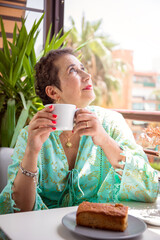 Woman who has overcome cancer having a coffee on her terrace.
