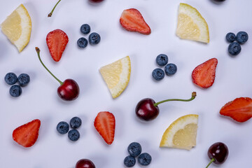 background of blueberries, strawberries, cherries and lemon slices on a white background - the concept of a healthy diet. Summer bright food fruit background, food design