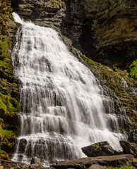 Impresionante cascada de un río de alta montaña que cae entre rocas por el barranco