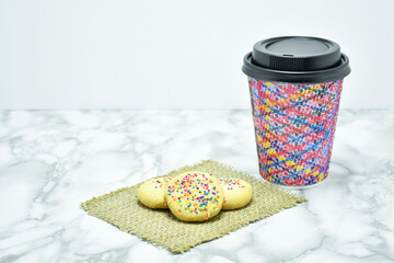 Galletas de Harina horneadas y cafe servido en un vaso desechable. Espacio para texto al lado...