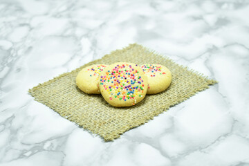 Galletas de harina horneadas bañadas con dulces de colores sobre una mesa.