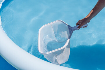 Woman cleaning her home's pool with a net
